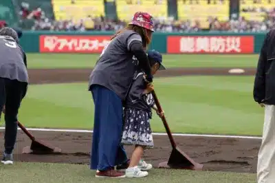 野球場でグラウンド整備をする親子