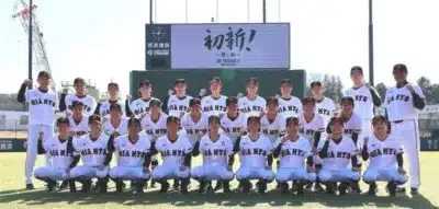 野球場でユニフォーム姿の女子野球チーム「GIANTS」の選手とスタッフが集合写真を撮影しています