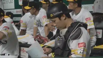 ベンチで書類を確認するキャッチャー