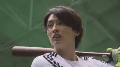 バットを肩に担ぎ見上げる選手