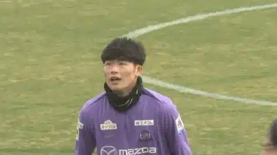 緑のグラウンドで紫色のユニフォームを着た若い男性サッカー選手