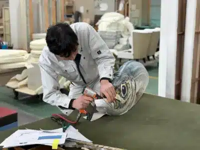 魚の形をしたオブジェを製作する職人