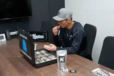 野球帽をかぶった男性が会議室で、ガムセレクションボックスからガムを選び口にしている様子