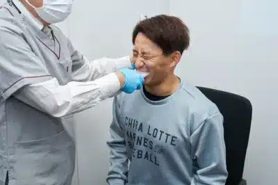 歯科医師が患者の口にマウスピースのような器具を装着している様子