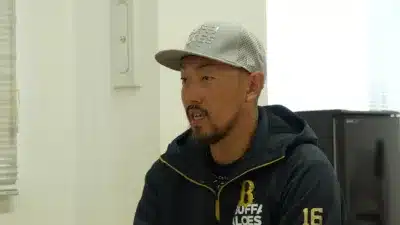 オリックス・バファローズのロゴが入ったキャップと背番号16のパーカーを着用した男性が話している様子