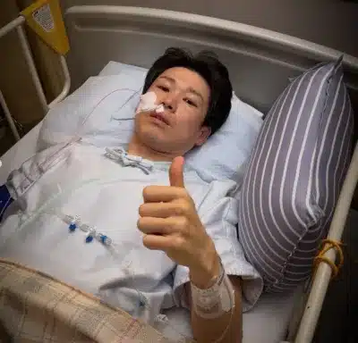 病院のベッドで親指を立てる福森さん