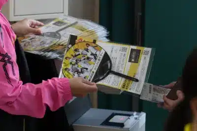 阪神甲子園球場での阪神タイガースの野球イベントで、auじぶん銀行デーの応援うちわとチラシを配っている様子