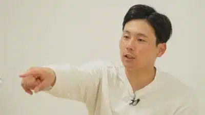 白いシャツを着た男性が、指を指しながら話している様子