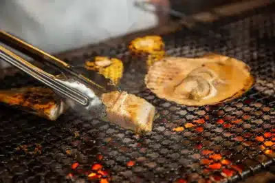 炭火で魚、ホタテ、トウモロコシが焼かれている様子