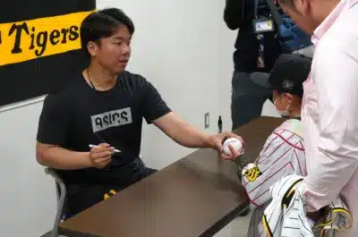 野球選手がイベントで子供にサインボールを渡している様子