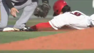 野球選手がヘッドスライディングでベースに滑り込んでいる瞬間を捉えた画像。土埃が舞い上がり、試合の緊迫感が伝わります。