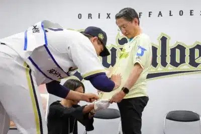 ユニフォームにサインをする九里投手