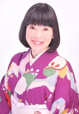 紫色の華やかな花柄の着物を身につけた、笑顔の女性(水田わさびさん)