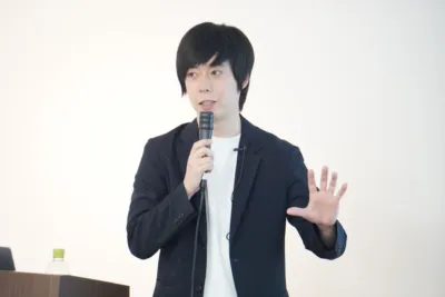 髙橋朋己氏がマイクを持って話す写真