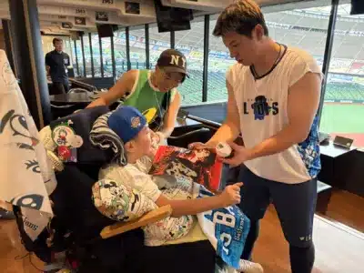 野球選手が車椅子の子供と交流しサインボールを渡す様子