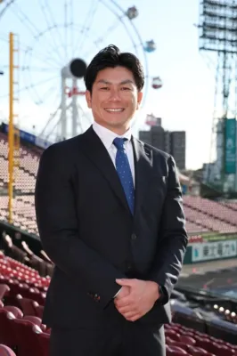 スーツを着て笑顔で立つ岡島豪郎氏