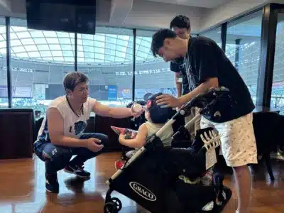 野球選手がベビーカーの子供に優しく野球ボールを見せ交流する様子