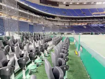 空の野球スタジアムの内部を、フィールドに近い観客席から撮影した写真。前方には快適そうなシートが並び、その奥には広大な青い観客席が広がっている。試合がない日の静かなドームの様子がうかがえる。