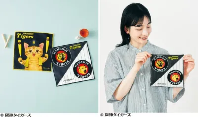 阪神タイガースのロゴと猫のキャラクターがデザインされたハンカチ2種類と、そのうちの1枚を笑顔の女性が持っている様子を捉えた画像です。野球ファン向けの可愛らしいグッズが紹介されています。