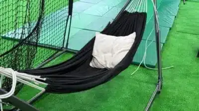 緑色の人工芝が敷かれた空間に、黒いハンモックと白いクッションが設置されています