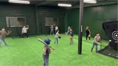 室内練習場で野球の練習をする子供たちの様子