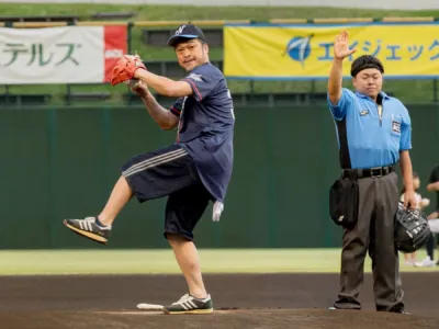 野球場でピッチャーが投球モーションに入り、審判が横に立っている