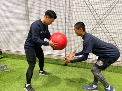 室内トレーニング施設でメディシンボールを使ったトレーニングをする男性たち