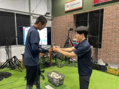 室内スポーツ施設でピッチングトレーニングをする男性とデータ表示