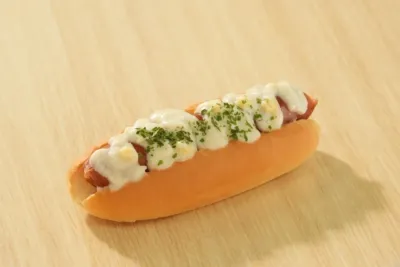 白いソースとパセリがトッピングされたホットドッグ