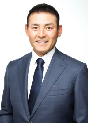 紺色のチェック柄スーツとネクタイを着用し微笑む川上憲伸氏