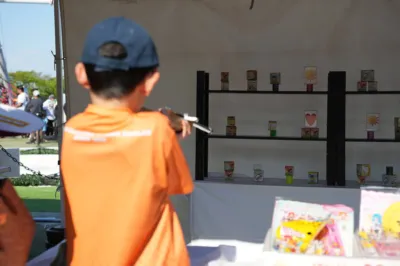屋外イベントの射的ゲームでターゲットを狙う男の子