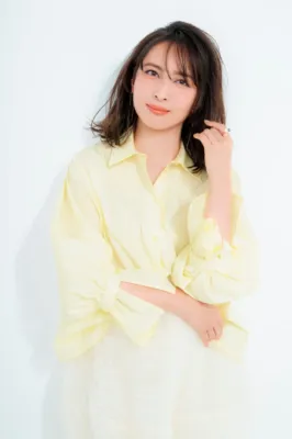 白い背景のスタジオで、淡い黄色のブラウスと白いスカートを着用した加藤夏希さん