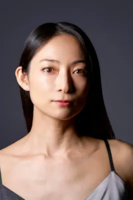 暗い背景の前でカメラを見つめる松本英子さんのポートレート