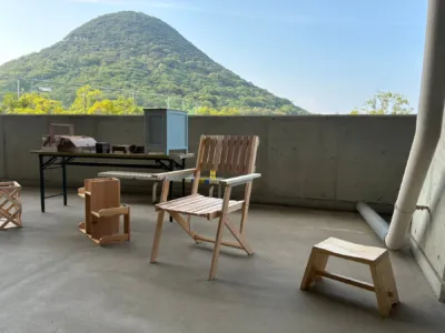 木製の椅子やスツールが並べられた屋外展示