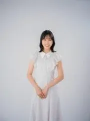 白い襟付きのフリル袖ドレスを着た若い日本人女性が、白い背景の前で微笑んでいます。明るい雰囲気のポートレート写真です。